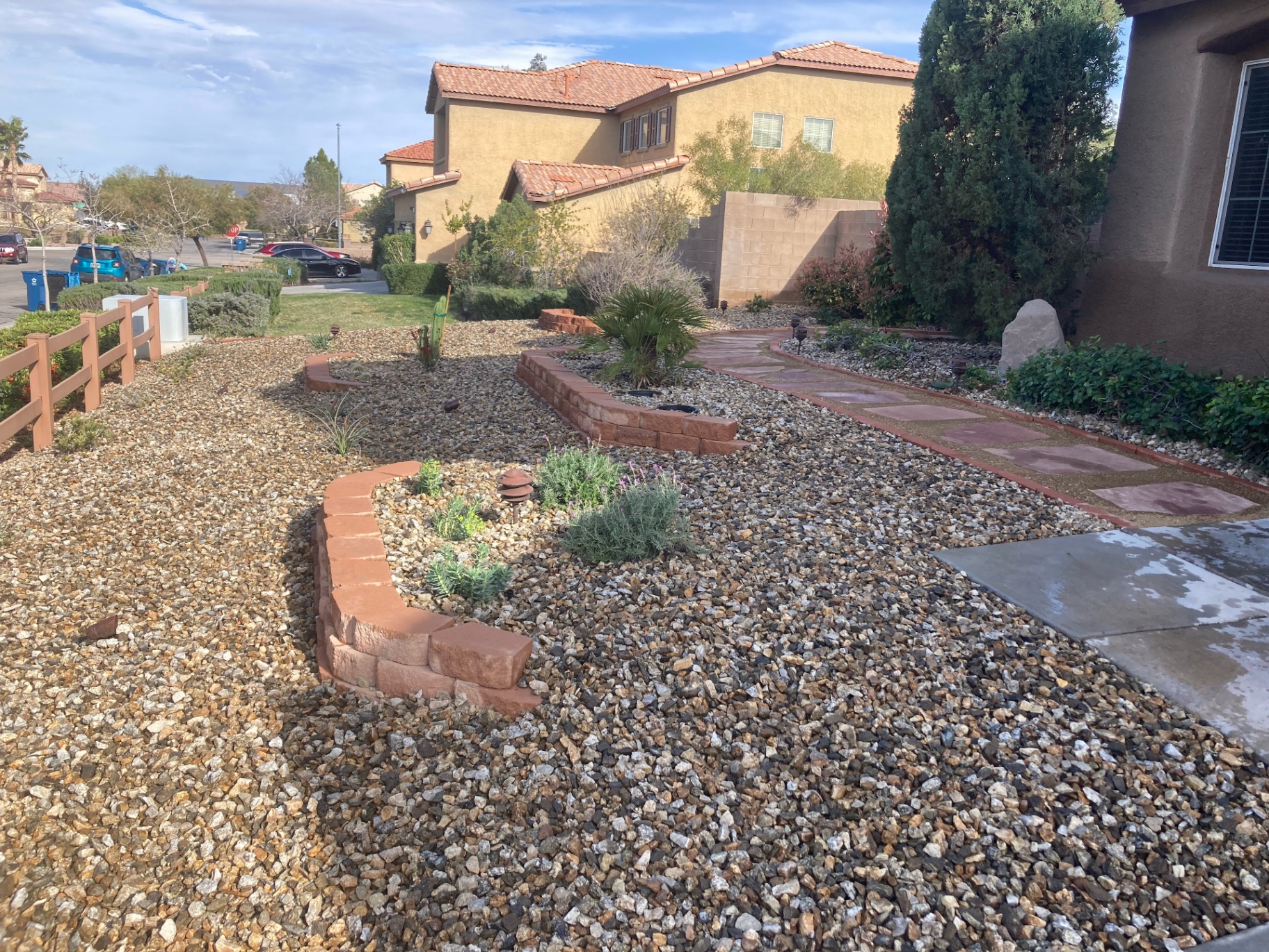 Finished xeriscape front yard with gravel, succulents, and stone borders