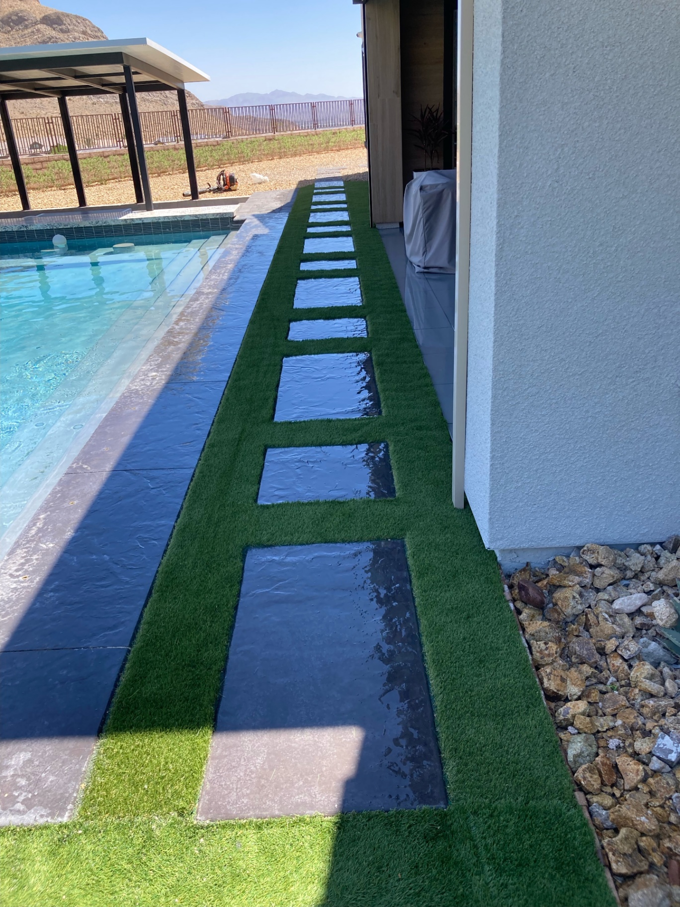 Poolside turf strip with dark stone steppers and mountain view