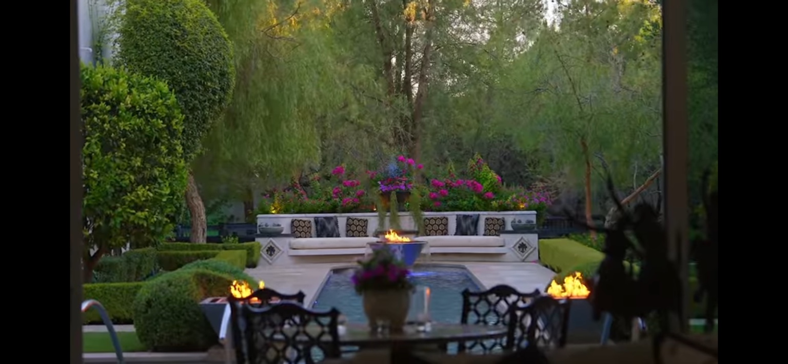 Formal garden fountain framed by flowers and mature trees
