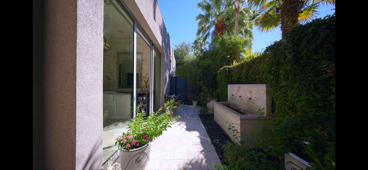 Maintained side garden with flowering planters and clipped hedges