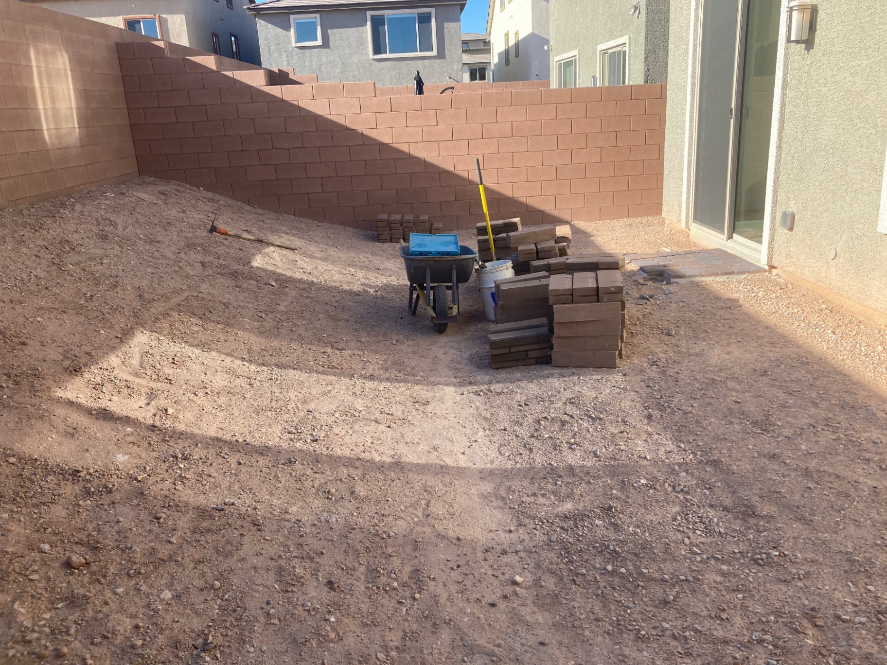 Backyard paver installation in progress with material staged