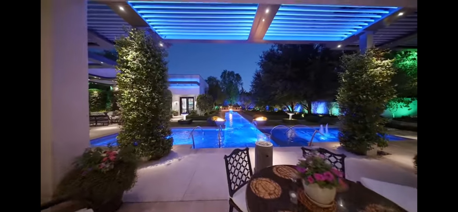 Pool terrace with evening landscape lighting and trimmed hedges