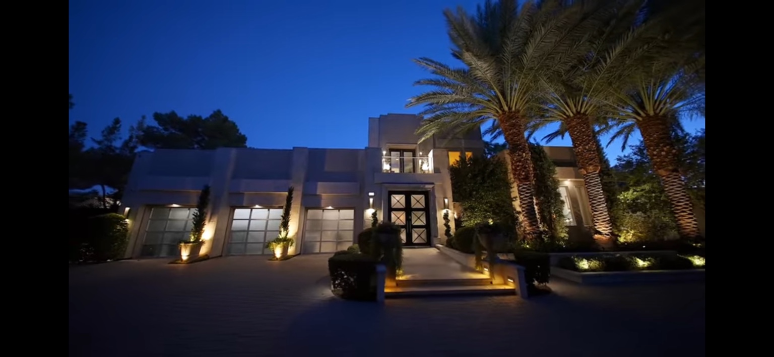 Estate front exterior and palms illuminated after dusk