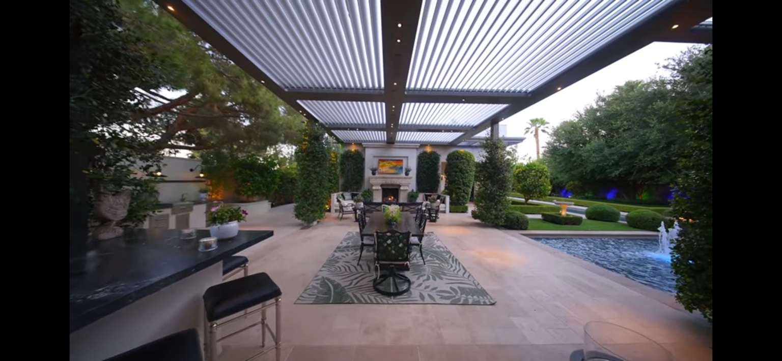 Covered outdoor dining terrace overlooking a maintained pool garden
